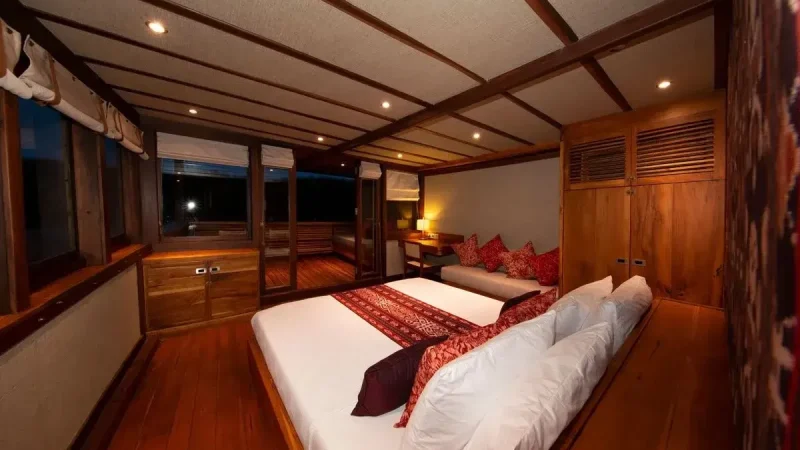 Cabin aboard a wooden vessel panelled and ceiled in varnished timber with a fitted berth