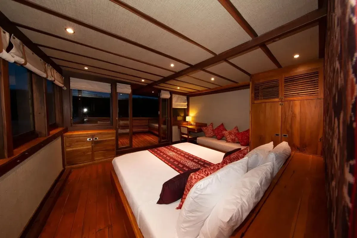 Cabin aboard a wooden vessel panelled and ceiled in varnished timber with a fitted berth