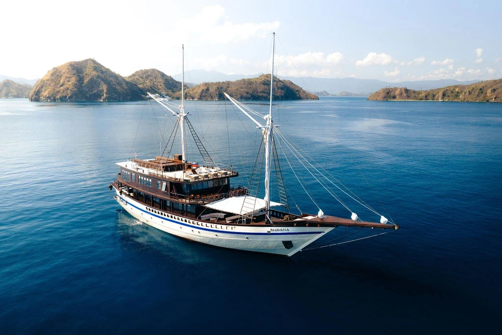 Wooden vessel lying at anchor in open water before a delivery passage