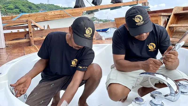 Two build supervisors kneeling on deck sorting and checking stainless deck fittings