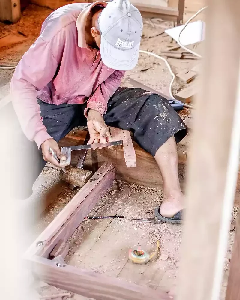 Shipwright shaping a joinery detail on the deck of a wooden vessel