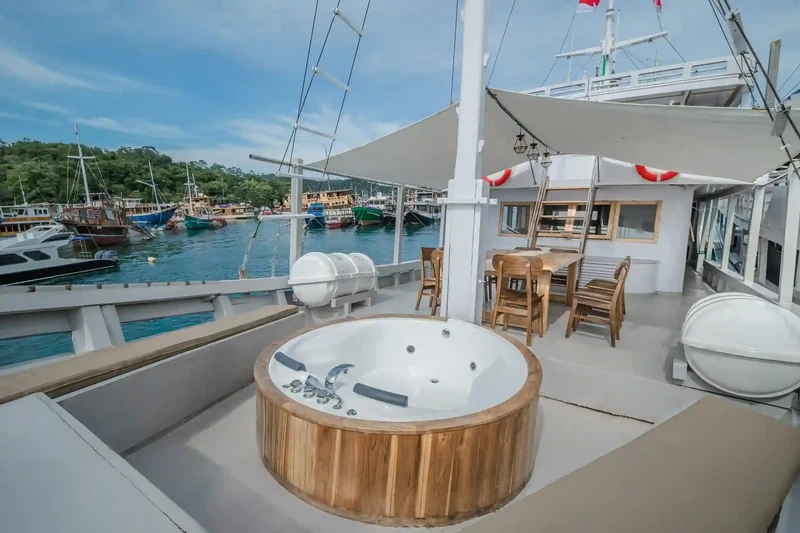 Open sun deck of a wooden liveaboard with timber decking and a deck tub forward