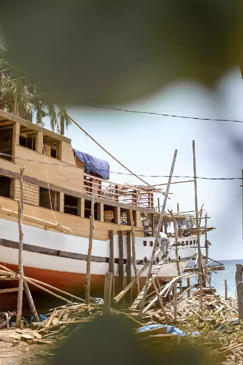 Timber superstructure and deckhouse of a phinisi taking shape over the finished hull