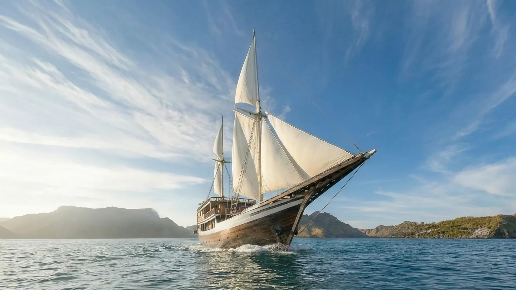 Wooden phinisi under full sail on open water under a high sky