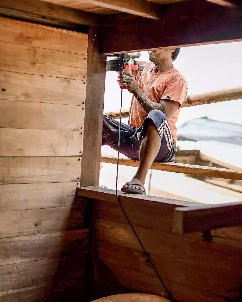 Shipwright working inside the timber superstructure of a wooden hull during fit-out