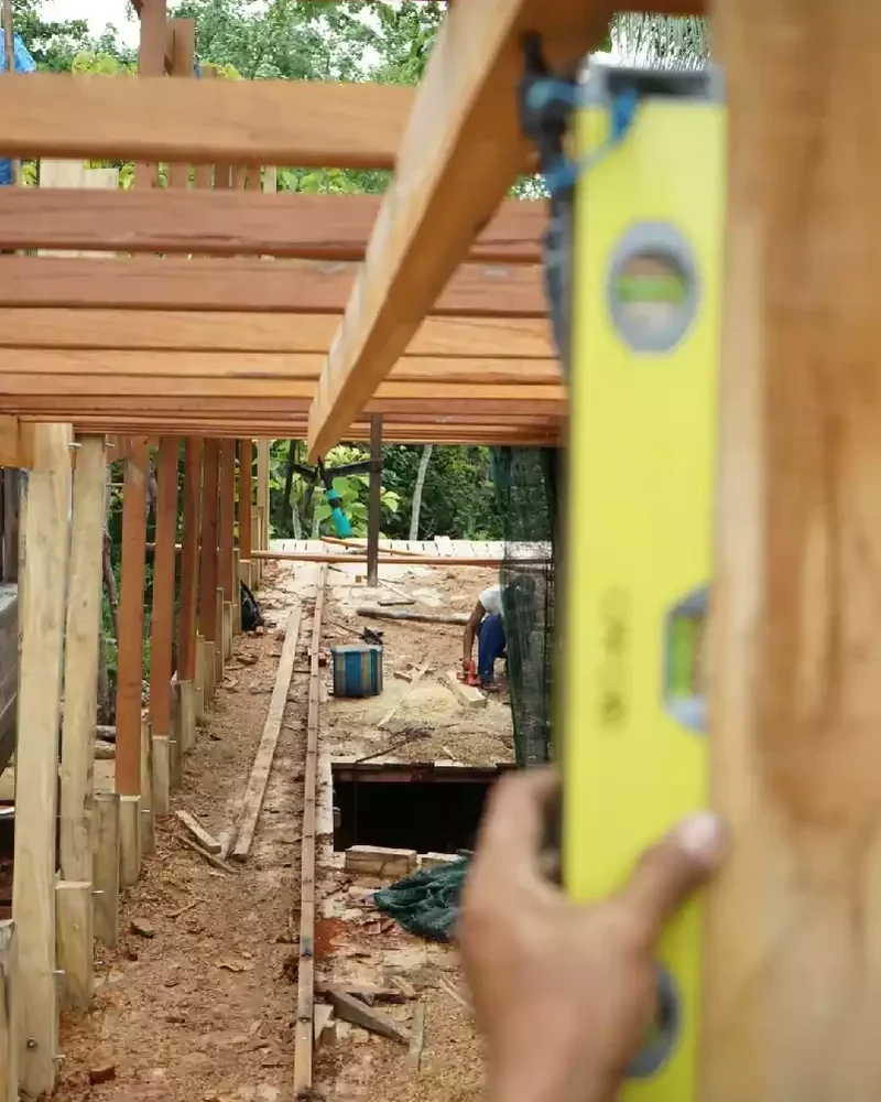 Spirit level held against timber framing inside a hull under construction during a milestone check