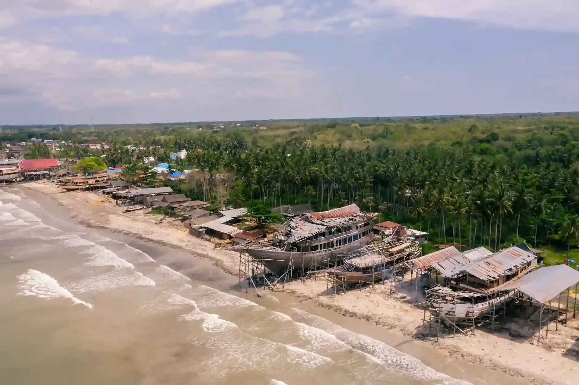 Aerial view of a stretch of beach boatyards with hulls standing along the shoreline