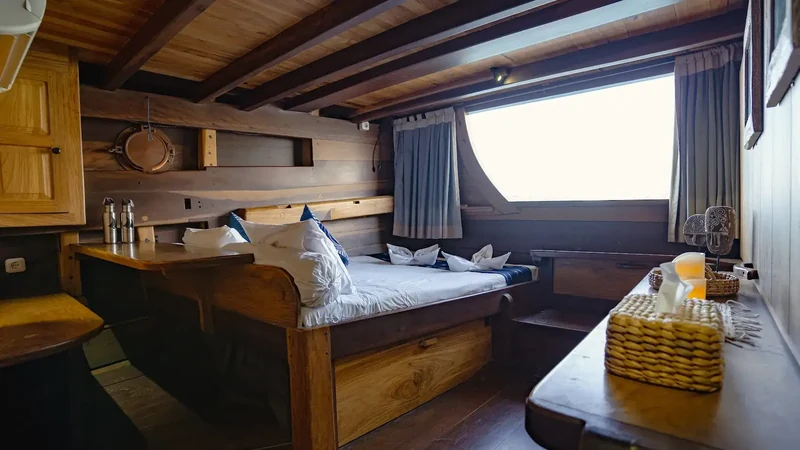 Cabin interior panelled in timber with fitted joinery, berth and a side window