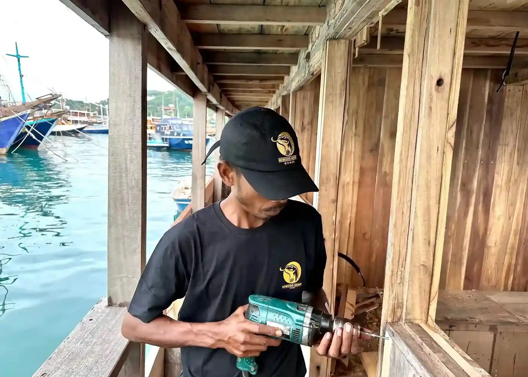 Shipwright working with a power tool on a hull moored at the water's edge